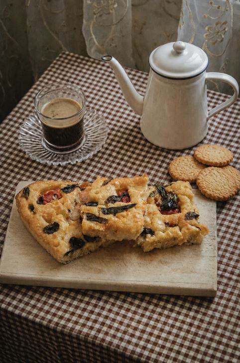 A tray of Italian focaccia with olives, dimpled and glistening with olive oil.